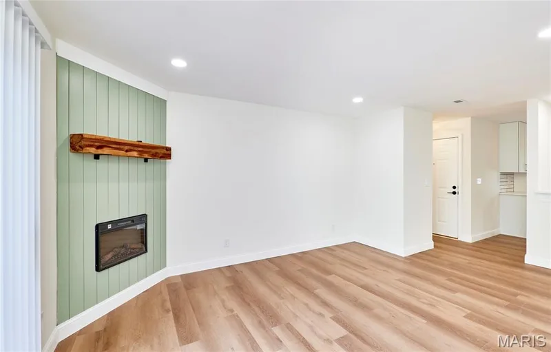Spacious living room featuring wood-finish Luxury vinyl plank flooring, recessed lighting, and a sliding glass door leading to an outdoor deck — 214 Sugar Lake Drive #5, St Peters, MO 63376