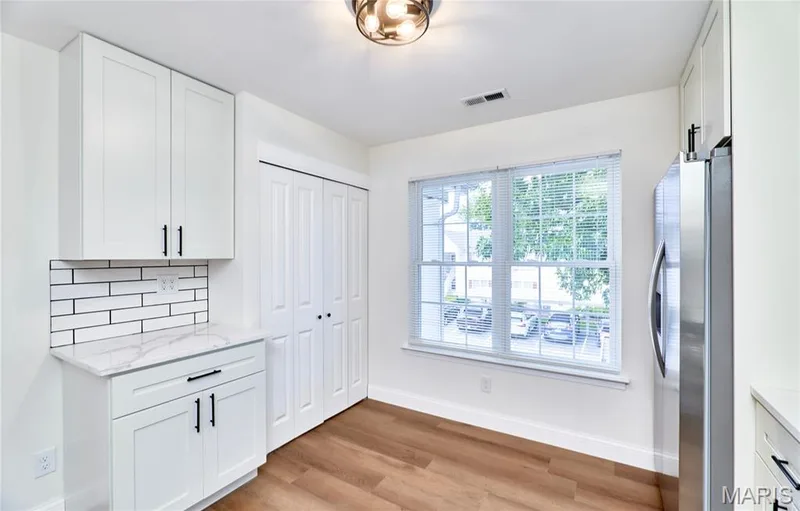 Bright kitchen featuring white shaker-style cabinetry with matte black hardware, stainless steel appliances, and wood-finish Luxury vinyl plank flooring — 214 Sugar Lake Drive #5, St Peters, MO 63376