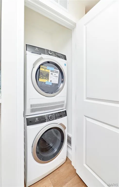 Dedicated laundry closet featuring a stacked washer and dryer unit,  wood-finish Luxury vinyl plank flooring and white paneled doors — 214 Sugar Lake Drive #5, St Peters, MO 63376