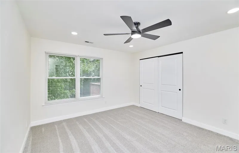 Bright bedroom featuring a large window, a ceiling fan with integrated lighting, recessed ceiling lights, and a double-door closet — 214 Sugar Lake Drive #5, St Peters, MO 63376