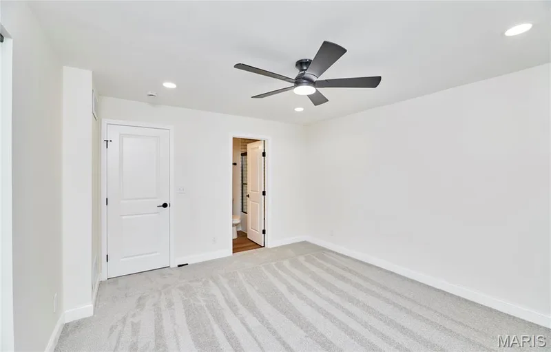Spacious bedroom featuring light gray carpeting, a contemporary black ceiling fan with integrated lighting, and recessed ceiling lights — 214 Sugar Lake Drive #5, St Peters, MO 63376