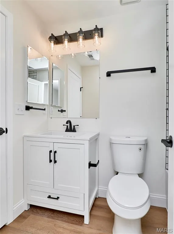 Contemporary bathroom featuring a white vanity with integrated sink, matte black fixtures, and wood-finish Luxury vinyl plank flooring — 214 Sugar Lake Drive #5, St Peters, MO 63376