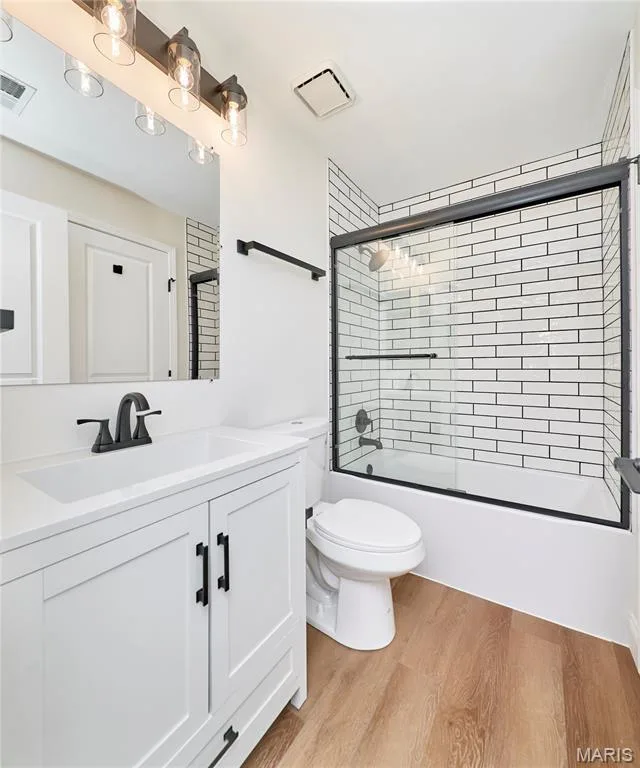 Bathroom featuring a white vanity with integrated sink, black hardware, and wood-finish Luxury vinyl plank flooring — 214 Sugar Lake Drive #5, St Peters, MO 63376
