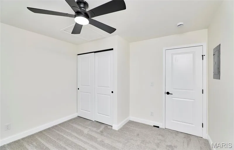 Spacious bedroom featuring neutral carpeting, a contemporary ceiling fan with integrated lighting, and white baseboards — 214 Sugar Lake Drive #5, St Peters, MO 63376