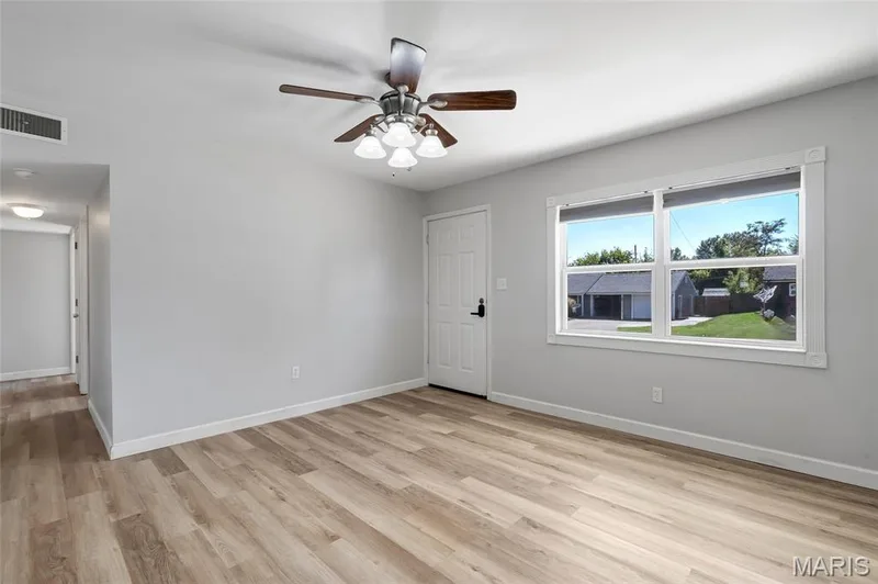 Interior space featuring wood-finish flooring, a multi-light ceiling fan, and a large window with exterior exposure — 503 Eggering Drive, O'Fallon, MO 63366