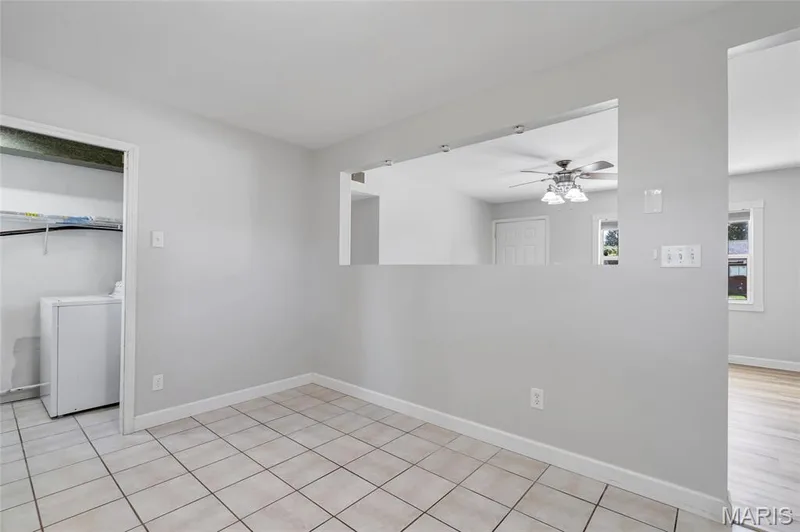 Neutral-toned interior featuring ceramic tile flooring, a recessed wall opening, and a dedicated laundry area with overhead shelving — 503 Eggering Drive, O'Fallon, MO 63366