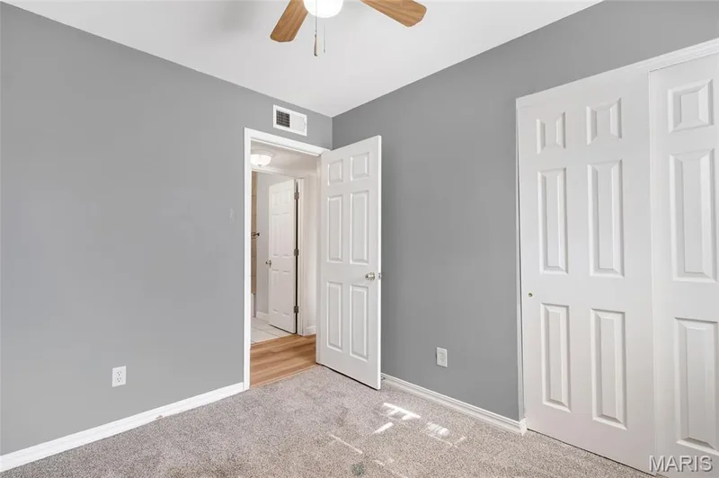 Neutral gray wall finishes, dual-panel closet doors, and a ceiling-mounted light fixture with a multi-blade fan — 503 Eggering Drive, O'Fallon, MO 63366