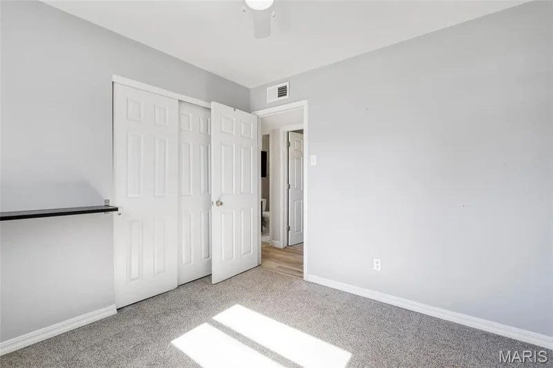 Neutral interior featuring light gray walls, plush carpeting, white six-panel closet doors, and a ceiling-mounted light fixture — 503 Eggering Drive, O'Fallon, MO 63366
