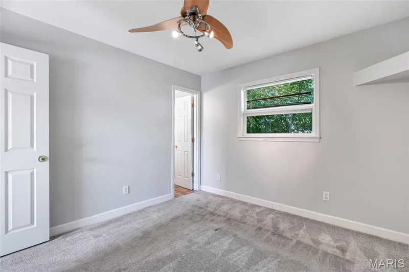 Room featuring neutral wall tones, wall-to-wall carpeting, a multi-blade ceiling fan with integrated lighting, and a single-hung window — 503 Eggering Drive, O'Fallon, MO 63366