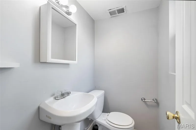 Wall-mounted mirrored cabinet, white pedestal sink with chrome faucet, and low-profile toilet — 503 Eggering Drive, O'Fallon, MO 63366