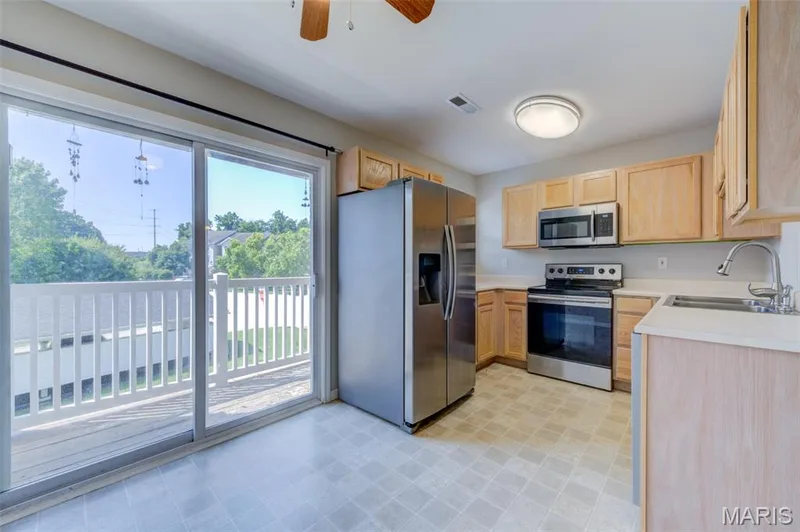 Stainless-steel appliances and well-maintained kitchen cabinets.  You can see the private balcony through the sliding door. — 480 Benton Drive #F, St Peters, MO 63376
