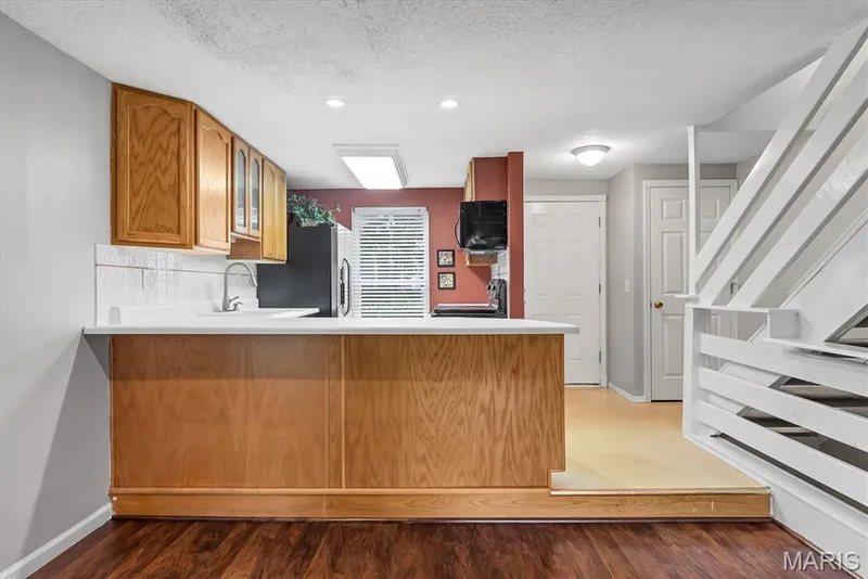 Kitchen bar with wood paneling, white countertop, and tile backsplash — 43 Breezy Knoll Lane, Lake St. Louis, MO 63367