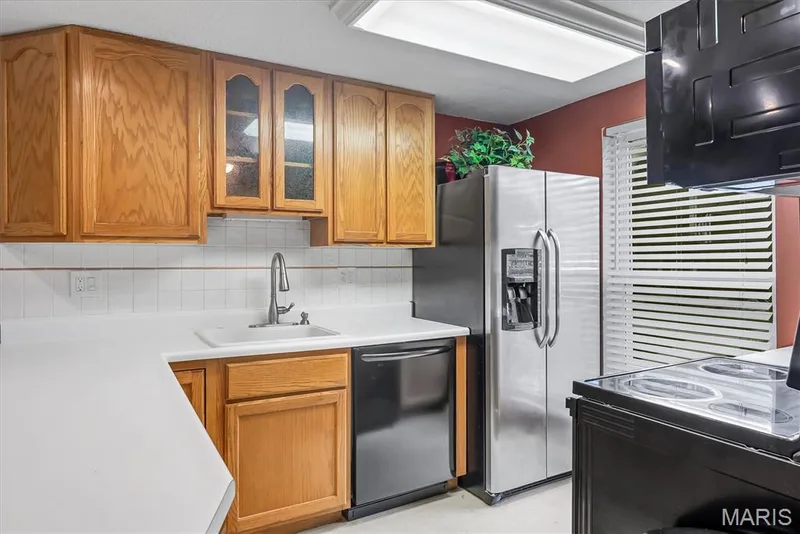 Kitchen featuring natural wood cabinetry, white countertops, stainless steel side-by-side refrigerator, integrated dishwasher, and a tile backsplash — 43 Breezy Knoll Lane, Lake St. Louis, MO 63367