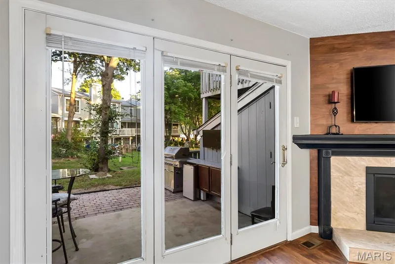 Glass-paneled French doors opening to an outdoor patio with brick paver accents — 43 Breezy Knoll Lane, Lake St. Louis, MO 63367