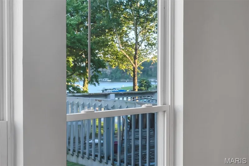 White-painted deck with wood railing overlooking a body of water with lush green trees and distant boats — 43 Breezy Knoll Lane, Lake St. Louis, MO 63367