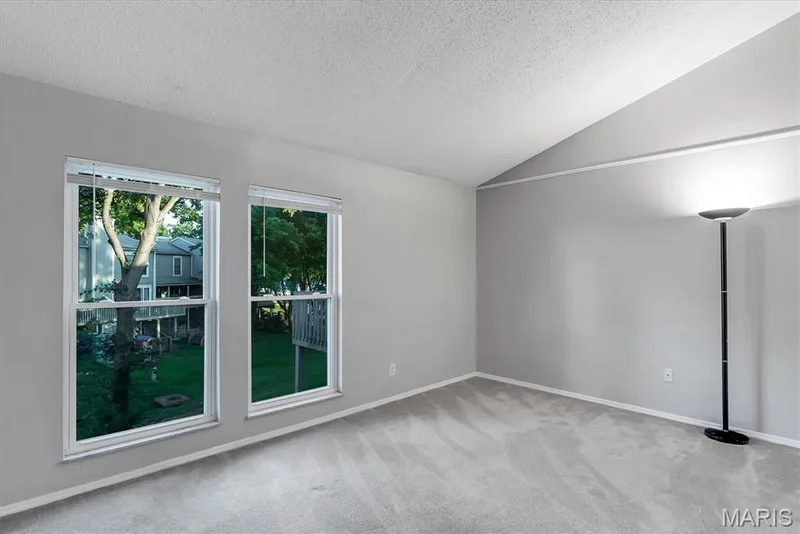 Room featuring two large windows with white blinds, grey carpet, light grey walls, and a vaulted ceiling — 43 Breezy Knoll Lane, Lake St. Louis, MO 63367