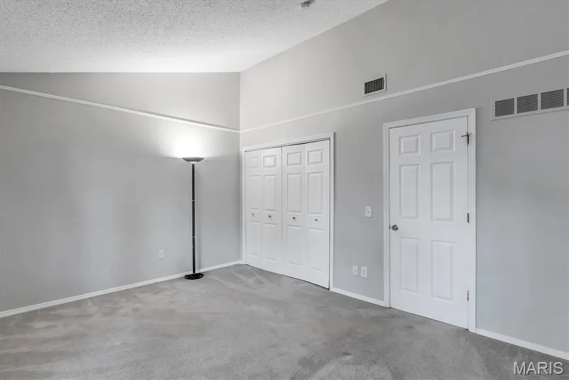 Vaulted ceilings enhance this room featuring light gray carpeting, crisp white baseboards, and a white six-panel door — 43 Breezy Knoll Lane, Lake St. Louis, MO 63367