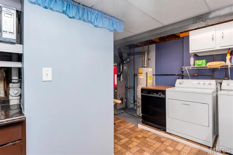 Utility area with full-size washer and dryer, built-in cabinetry, and water heater — 43 Breezy Knoll Lane, Lake St. Louis, MO 63367
