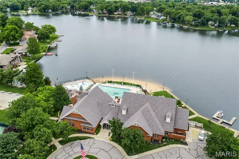 Expansive lakefront setting with a large brick-clad clubhouse featuring a multi-gabled roofline — 43 Breezy Knoll Lane, Lake St. Louis, MO 63367