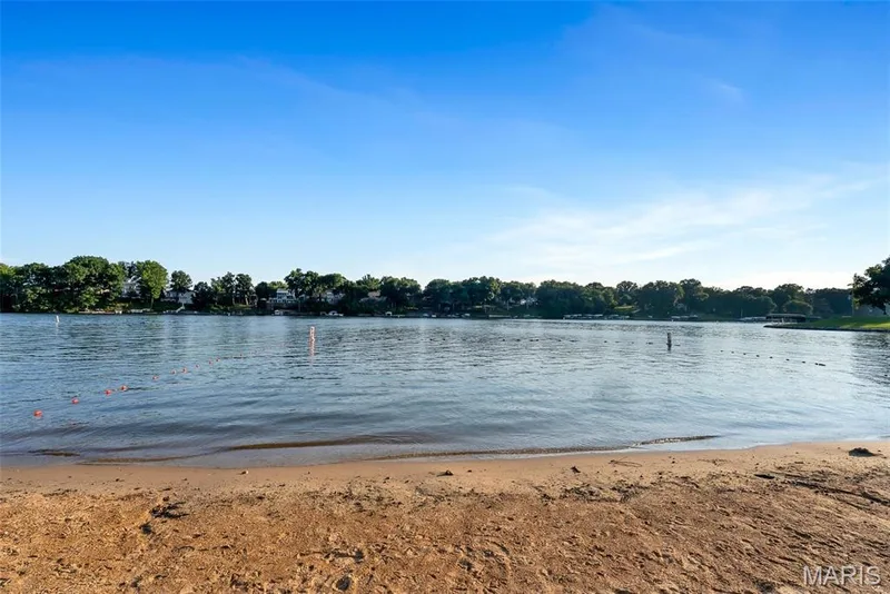 Sandy shoreline alongside calm waters, with a distant treeline and properties — 43 Breezy Knoll Lane, Lake St. Louis, MO 63367
