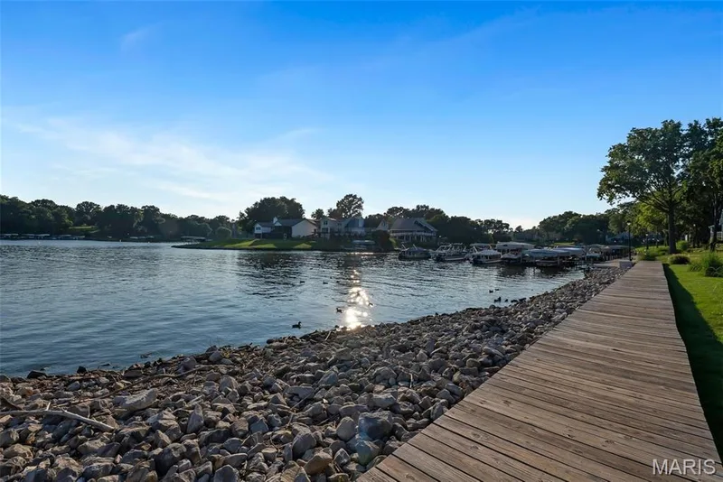 Waterfront setting featuring a wooden boardwalk, manicured green space, and a rocky shoreline — 43 Breezy Knoll Lane, Lake St. Louis, MO 63367