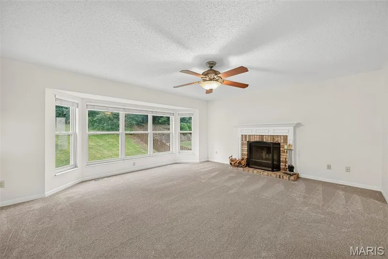 Spacious living area featuring a bay window, carpet flooring, and a ceiling fan — 4014 Treeshadow Drive, St Peters, MO 63376