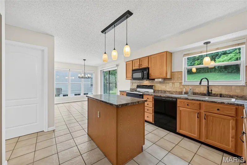 Kitchen featuring wood cabinetry, black appliances, a stone-look countertop, and a tiled backsplash — 4014 Treeshadow Drive, St Peters, MO 63376