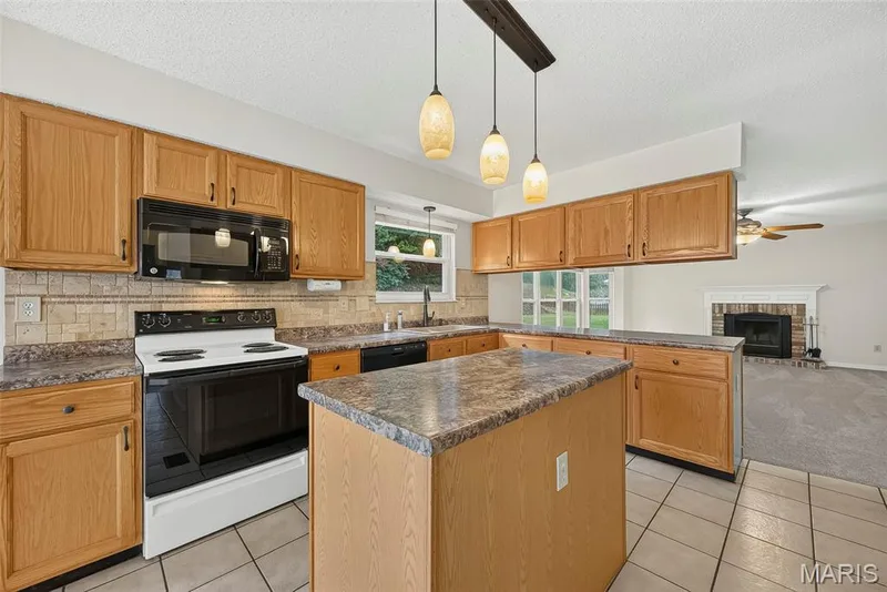 Kitchen featuring wood cabinetry, an island with countertop, and tile flooring — 4014 Treeshadow Drive, St Peters, MO 63376