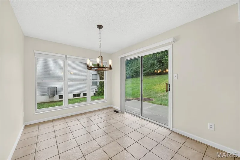 Dining area featuring a contemporary chandelier, large picture windows, and ceramic tile flooring — 4014 Treeshadow Drive, St Peters, MO 63376