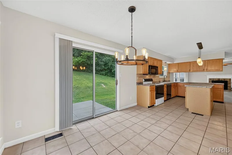 Kitchen and dining area featuring tile flooring, light wood cabinetry, and an island — 4014 Treeshadow Drive, St Peters, MO 63376