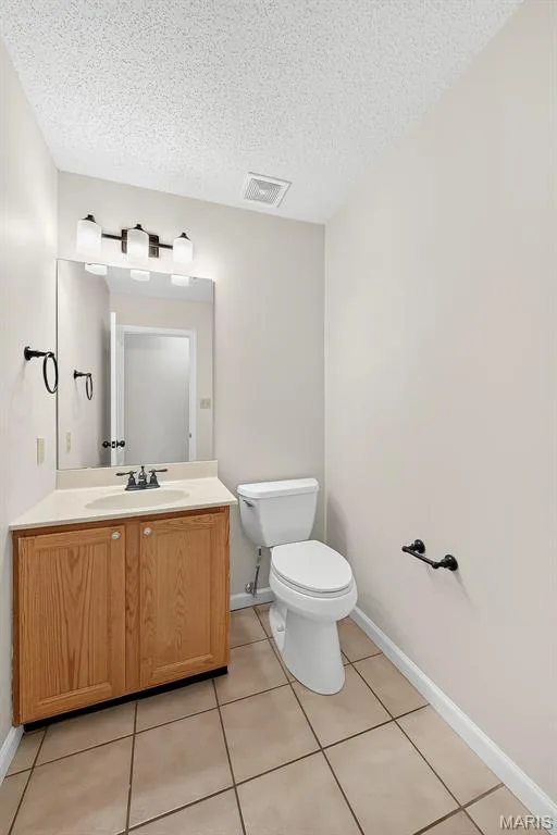 Bathroom featuring a wood-finish vanity with a light-toned countertop, a rectangular mirror, and a three-light vanity fixture — 4014 Treeshadow Drive, St Peters, MO 63376