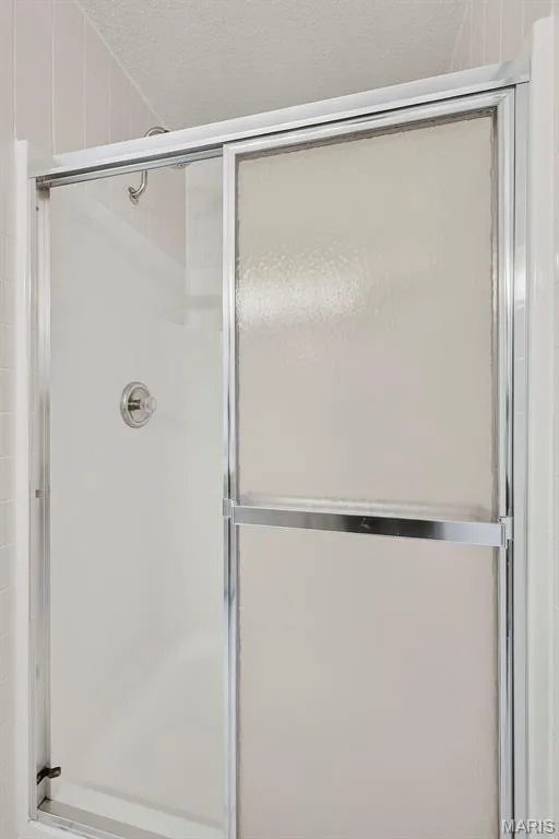 Shower enclosure with sliding frosted glass doors, chrome hardware, and a white acrylic shower surround — 4014 Treeshadow Drive, St Peters, MO 63376