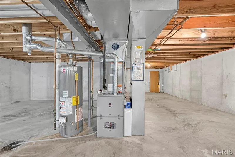 Unfinished basement featuring exposed wood joists, concrete foundation walls, and a concrete floor — 4014 Treeshadow Drive, St Peters, MO 63376