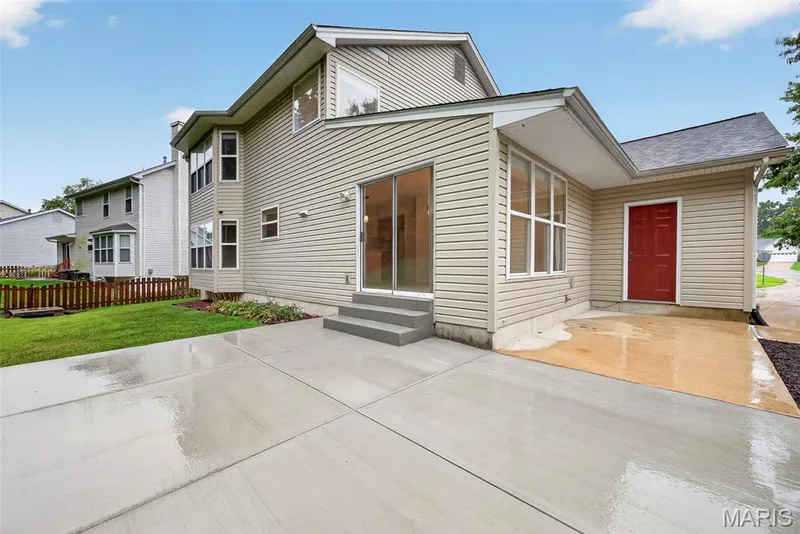 Expansive concrete patio with multiple access points, including a sliding glass door and an additional red exterior door — 4014 Treeshadow Drive, St Peters, MO 63376
