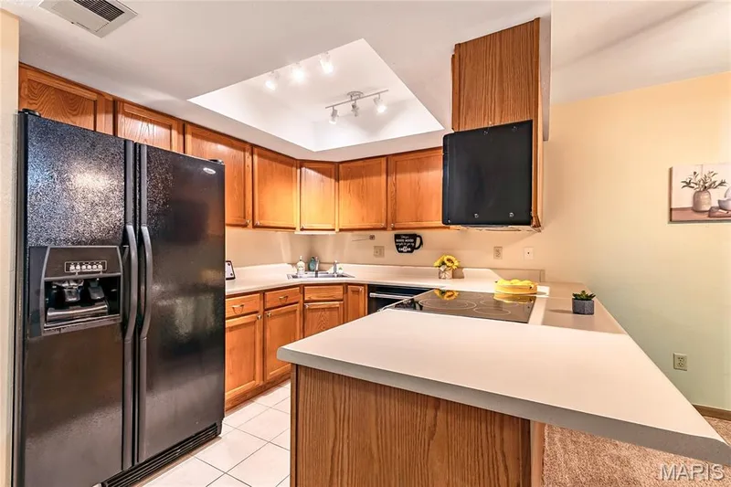 The kitchen features a built-in cooktop, dishwasher, microwave, and refrigerator (all to remain). — 1440 Heritage Landing #105, St Charles, MO 63303