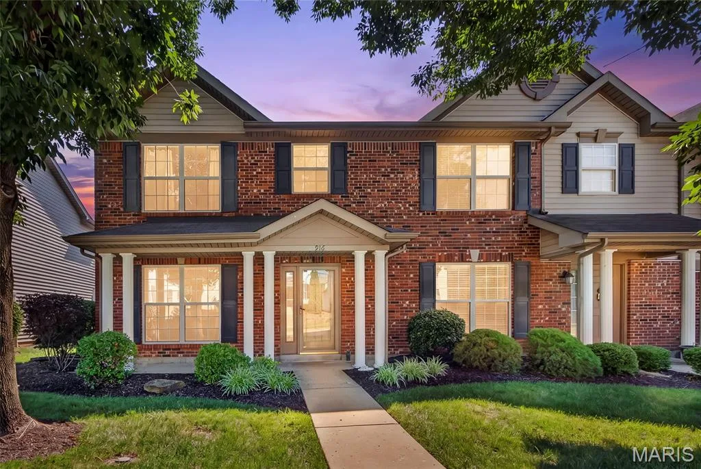 Brick facade residence with a covered porch featuring white columns and a central entryway with a glass-paneled door — 916 Carpathian Drive, Lake St. Louis, MO 63367