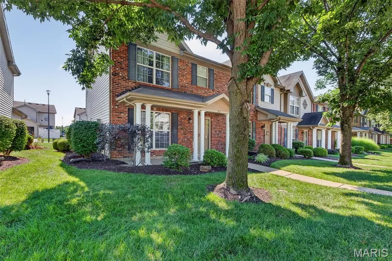 Brick and siding exterior featuring white columns, dark shutters, and a covered entry — 916 Carpathian Drive, Lake St. Louis, MO 63367
