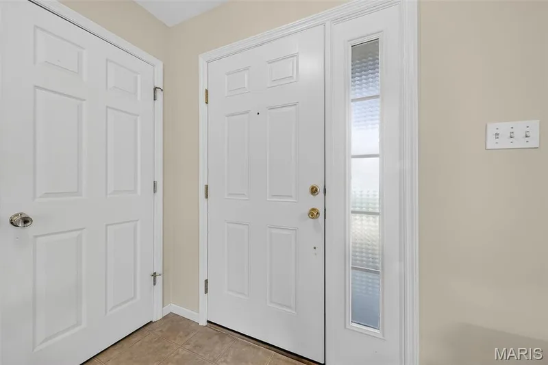 Entry foyer featuring a paneled door with brass hardware and a frosted glass sidelight — 916 Carpathian Drive, Lake St. Louis, MO 63367