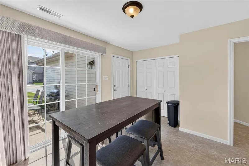 Kitchen area featuring a sliding glass door, neutral tile flooring, a semi-flush ceiling light fixture, a white paneled door, and bi-fold closet doors — 916 Carpathian Drive, Lake St. Louis, MO 63367