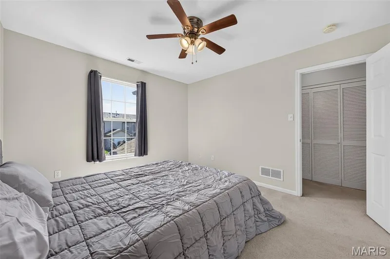 Bedroom featuring neutral wall paint, a window with white trim, and a ceiling fan with wood-finish blades — 916 Carpathian Drive, Lake St. Louis, MO 63367