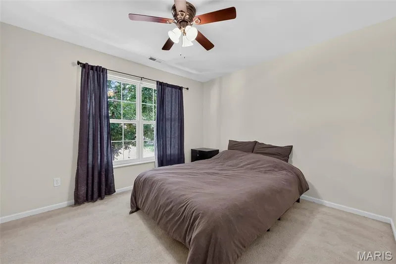 Carpeted room featuring a ceiling fan with light fixture, double-hung window, and light-colored walls — 916 Carpathian Drive, Lake St. Louis, MO 63367