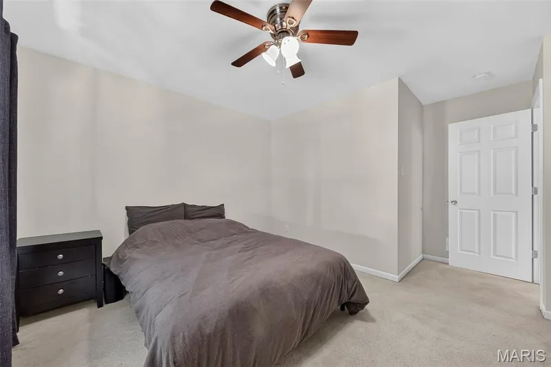 Bedroom featuring light neutral wall paint and carpeting, a ceiling fan with integrated lighting, and a white six-panel door — 916 Carpathian Drive, Lake St. Louis, MO 63367