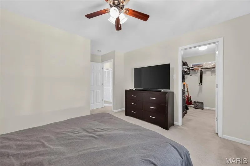Bedroom featuring light neutral wall paint, a ceiling fan with integrated lighting, and carpet flooring — 916 Carpathian Drive, Lake St. Louis, MO 63367