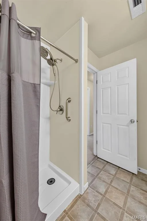 Walk-in shower with a modern brushed nickel showerhead and grab bar — 916 Carpathian Drive, Lake St. Louis, MO 63367