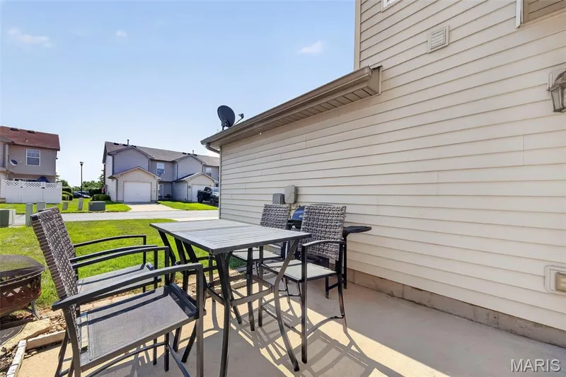 Concrete patio area with horizontal siding exterior, exterior lighting fixture, and a gridded satellite dish — 916 Carpathian Drive, Lake St. Louis, MO 63367