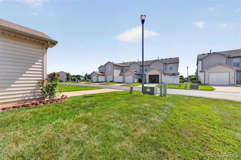 Exterior featuring siding, a landscaped border with greenery, and a sidewalk — 916 Carpathian Drive, Lake St. Louis, MO 63367