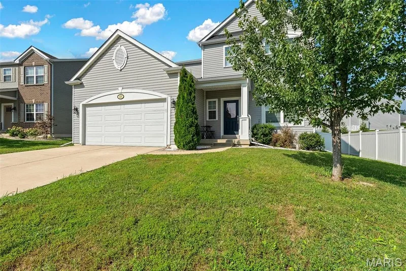 Charming two-story home featuring a clean white garage door, light-colored siding, and a well-defined front elevation with gable roofline — 225 Thorn Brook Drive, O'Fallon, MO 63366