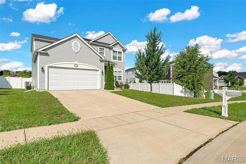 Two-story residence featuring light gray siding, a two-car garage, and a concrete driveway — 225 Thorn Brook Drive, O'Fallon, MO 63366