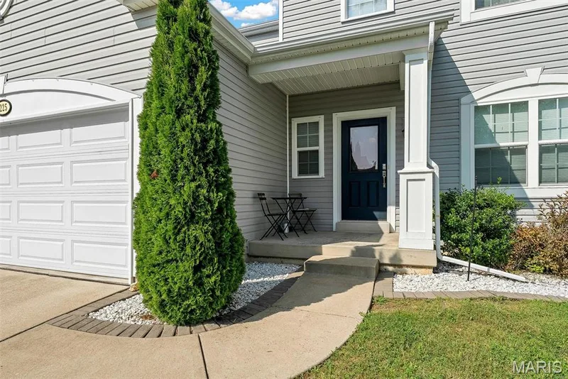 Exterior with light gray siding, white garage door, and a dark blue entry door — 225 Thorn Brook Drive, O'Fallon, MO 63366