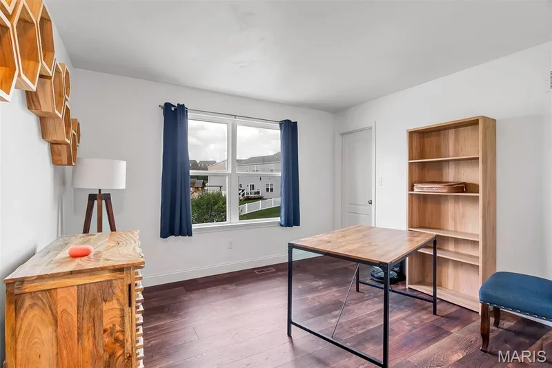 Bright interior space featuring a large window, dark wood-finish flooring, and white walls — 225 Thorn Brook Drive, O'Fallon, MO 63366